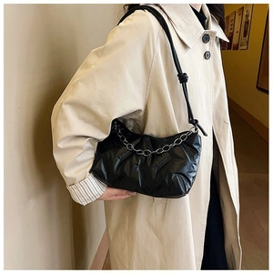 Détail du sac porté épaule plissé noir avec chaîne argentée sur mannequin en trench beige