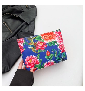 Detail of blue nylon clutch featuring ethnic floral patterns and colorful phoenix prints