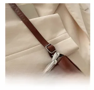 Détail d'un sac porté épaule en cuir marron avec chaîne cœur argentée et sangle réglable