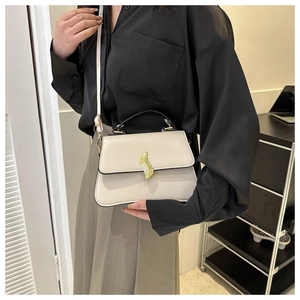 Détail de l'élégante boucle en métal doré sur un sac à bandoulière carré blanc crème