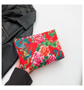 Close-up of ethnic nylon clutch bag with peony and phoenix print on red fabric