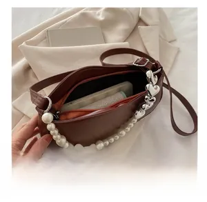 Détail de la capacité du sac en cuir marron avec bandoulières perle et chaîne coeur