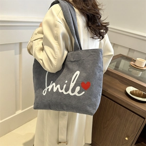 Blue corduroy tote bag with Smile print and red heart detail for women in a lifestyle setting