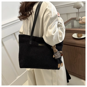 Détail d'un grand sac cabas en peluche noire avec patch fashion et breloque lapin porté
