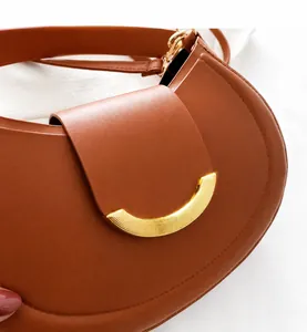 Detail showing smooth caramel brown leather texture and crescent golden metal buckle