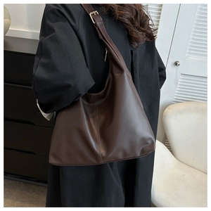 Detail view of large dark brown PU leather bucket bag with metallic shoulder strap buckle