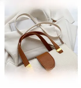 Close-up of litchi grain leather texture and gold hardware on beige handbag