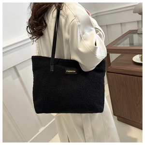 Vue latérale d'un sac cabas en polaire noire avec lanières en cuir porté à l'épaule