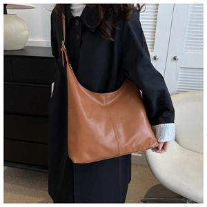 Detail of caramel faux leather shoulder bag with vertical stitching and adjustable strap