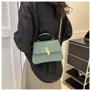 Sac à main vert avec fermoir feuille dorée porté par un mannequin pour le style