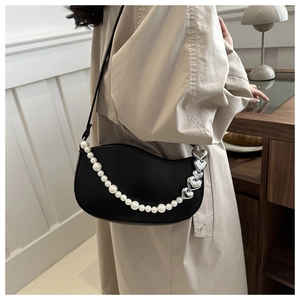 Détail du sac bandoulière noir en demi-lune avec chaîne perlée et pendentif coeur