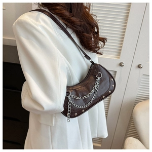 Détail du sac sous l'aisselle en cuir crocodile marron foncé avec chaîne argentée