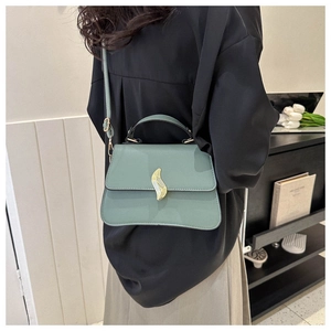 Détail du sac carré vert menthe avec fermoir doré porté par un mannequin