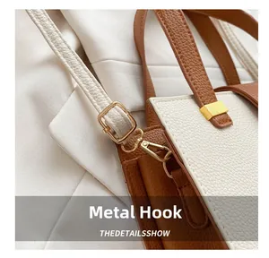Close-up of golden hardware and lychee grain leather on brown and beige crossbody bag