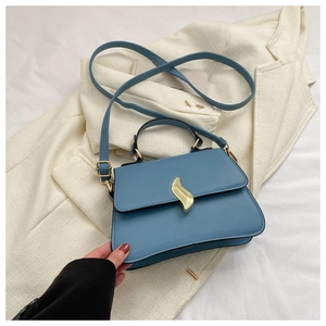 Détail du sac à main bleu morandi avec boucle flamme dorée sur tissu texturé élégant