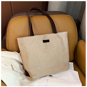Close-up of beige woven tote bag with brown leather straps on an office chair
