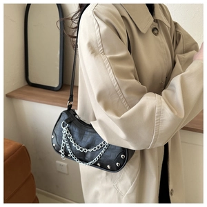 Détail du sac à aisselle noir aspect crocodile avec chaîne argentée et clous