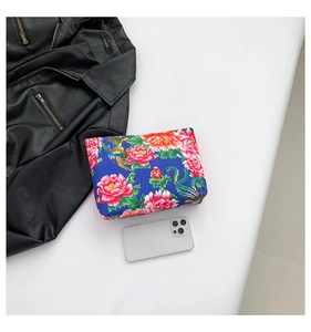 Ethnic blue satin clutch bag with red peony prints shown next to a smartphone
