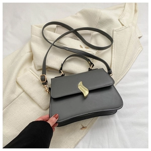 Détail du sac bandoulière en cuir gris avec boucle en métal doré en forme de S