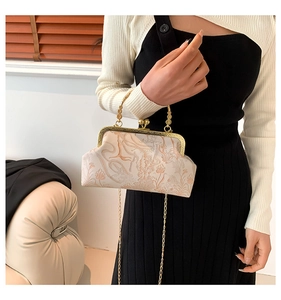 Detail of vintage beige kiss-lock bag with floral deer embroidery and gold metal handle