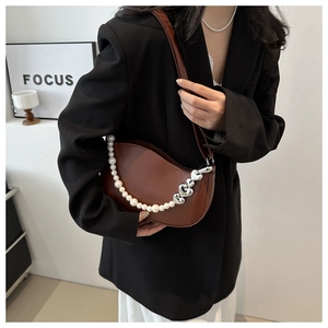 Détail d'un sac demi-lune en cuir marron avec une chaîne élégante de perles et de cœurs