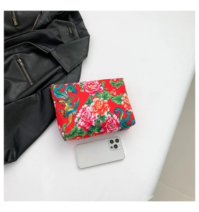 Macro view of red ethnic floral print bag with phoenix patterns next to a smartphone