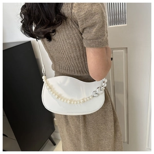 Détail du sac à épaule en cuir verni blanc avec chaîne en perles et bord ondulé