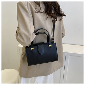 Litchi texture black tote bag side view on model with gold hardware detail