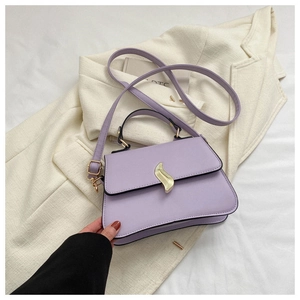 Détail d'un sac violet lavande avec fermoir doré posé sur une veste de costume