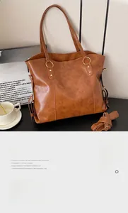 Detail view of large brown tote bag showing gold hardware and adjustable strap