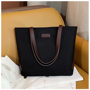 Detail of black canvas tote bag showing the brown leather straps and FASHION tag