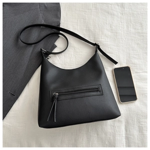 Detail of black litchi pattern tote bag with silver zipper pocket on white fabric