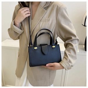 Detail of black pebbled leather handbag with gold hardware and stylish square structure