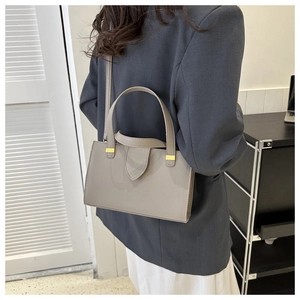 Taupe pebbled leather handbag shown in a professional commute style on a model