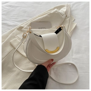 Detail of white leather saddle bag showing gold crescent buckle and smooth texture