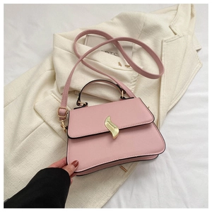 Vue détaillée de dessus d'un sac à main rose avec fermoir doré sur une veste blanc cassé
