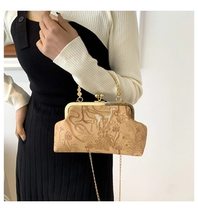 Detail of vintage beige kiss-lock chain bag with embossed deer and floral patterns