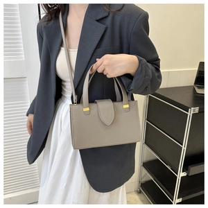 Detail of taupe litchi grain faux leather handbag with gold metal buckle and flap
