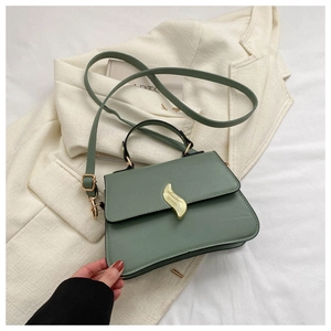 Détail du sac à main vert sauge avec boucle dorée et texture de cuir délicate