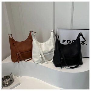Three minimalist large capacity tote bags in caramel, black and white on display pedestals