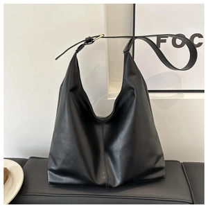Close-up of matte black leather hobo bag with vertical stitching and metal buckle strap