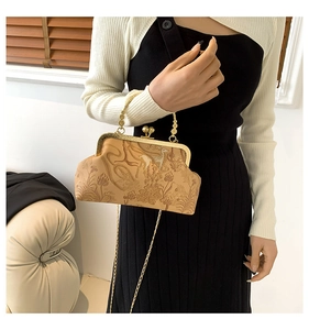 Detail of vintage beige kiss-lock bag with floral deer embossing and dual chain straps