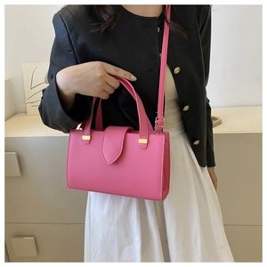 Detailed view of magenta textured leather handbag with gold buckle and adjustable strap