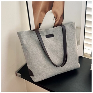 Detail of off-white linen tote bag showing fashion leather patch and brown straps