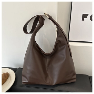 Detail of dark brown leather hobo bag featuring wide strap and golden square buckle