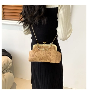 Detail of floral embossed vintage frame bag with gold clasp and metal chain strap
