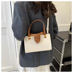 Detail view of cream lychee leather handbag with brown handles and gold metal hardware