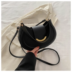Minimalist black matte hobo bag with gold metal clasp on a stylish lifestyle background