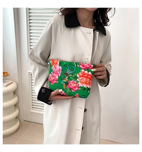 Ethnic style clutch with floral phoenix print held by model in cream coat