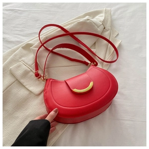 Detail of red leather saddle bag featuring a prominent crescent-shaped gold metal clasp